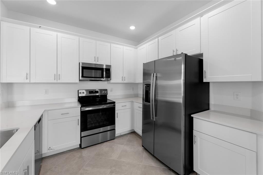 2856 Citrus Street Naples, FL 34120 - Photo 6 of 20 Kitchen featuring stainless steel appliances, white cabinetry, recessed lighting, light tile patterned floors, and light stone counters