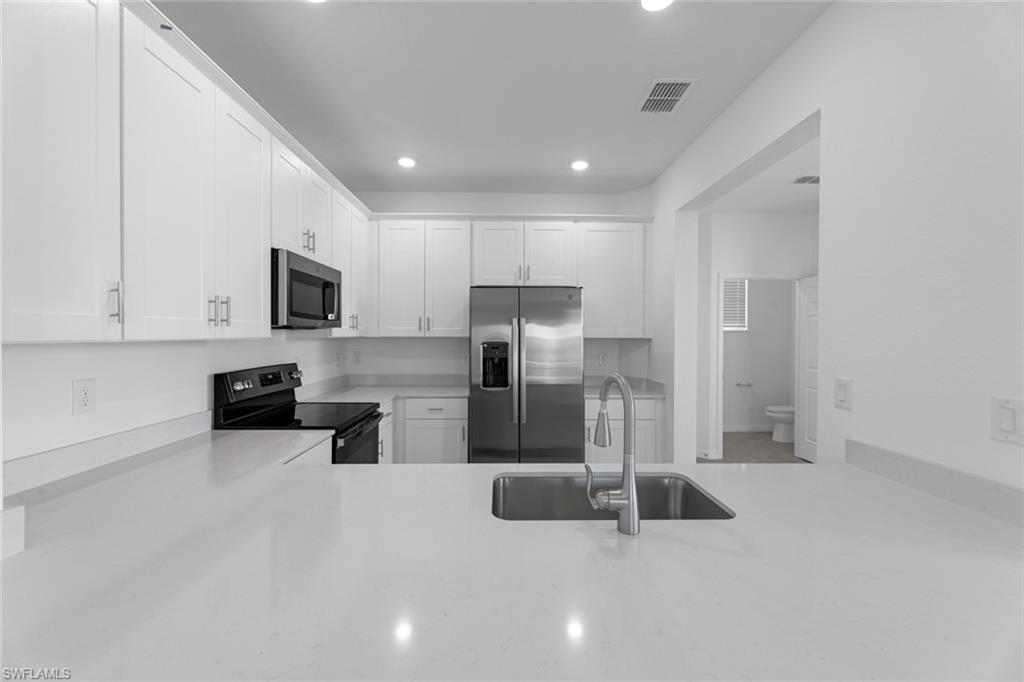 2856 Citrus Street Naples, FL 34120 - Photo 7 of 20 Kitchen with white cabinets, appliances with stainless steel finishes, recessed lighting, and light stone counters
