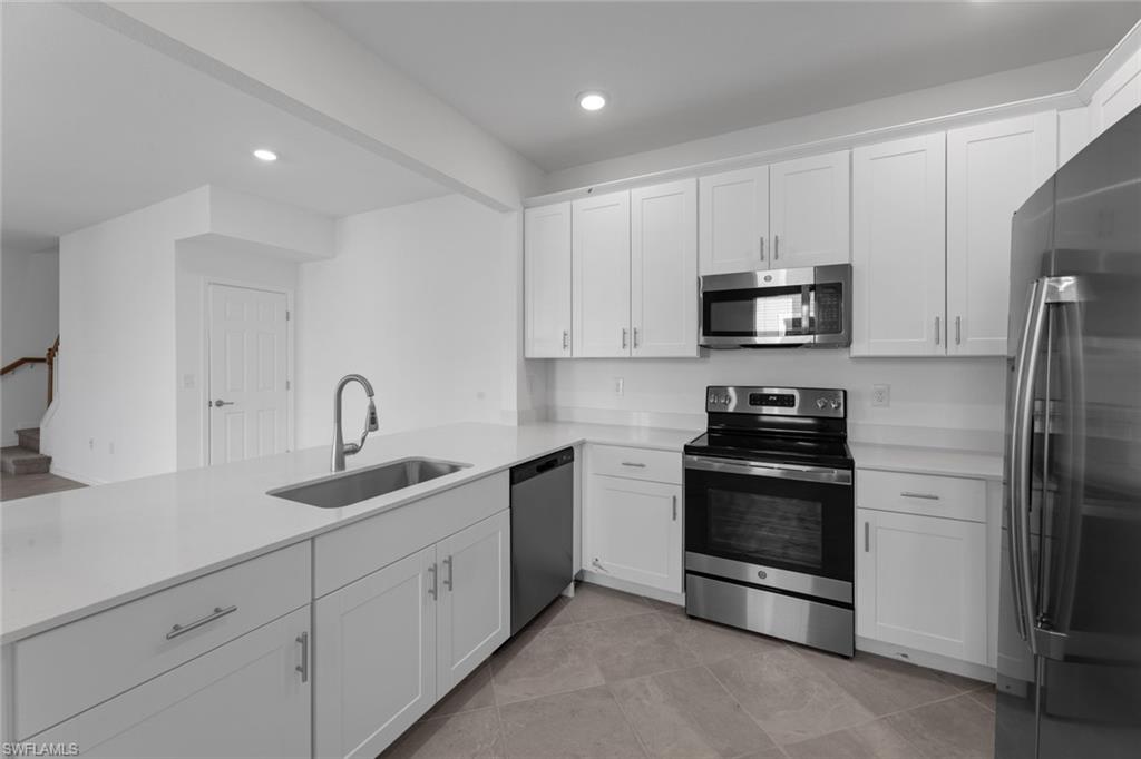 2856 Citrus Street Naples, FL 34120 - Photo 8 of 20 Kitchen featuring appliances with stainless steel finishes, white cabinetry, recessed lighting, light stone counters, and a peninsula