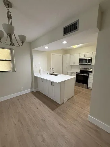 a large kitchen with a sink stainless steel appliances and counter space