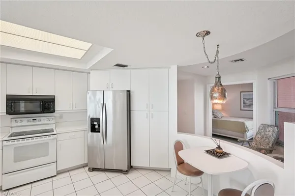 a kitchen with stainless steel appliances kitchen island granite countertop a refrigerator a stove a sink dishwasher and a dining table with wooden floor