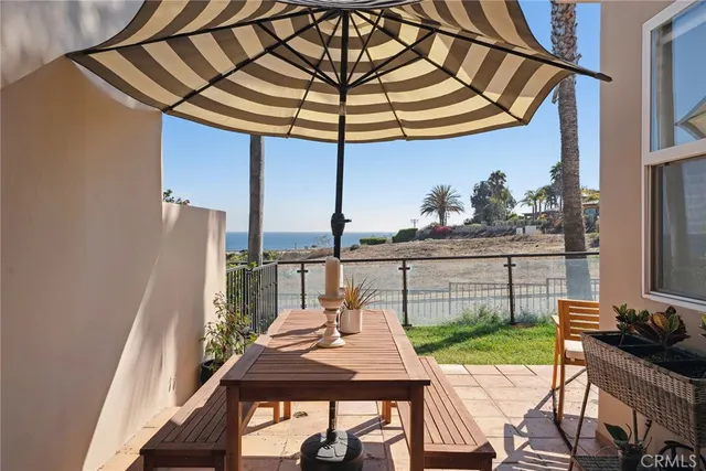 a view of a patio with table and chairs under an umbrella with a small yard