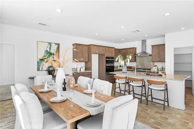 a dining room with stainless steel appliances kitchen island granite countertop a dining table chairs and a refrigerator