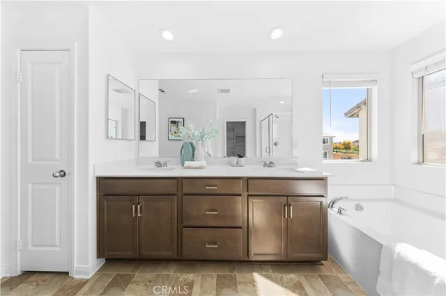 a spacious bathroom with a granite countertop double vanity sink a mirror and a bathtub