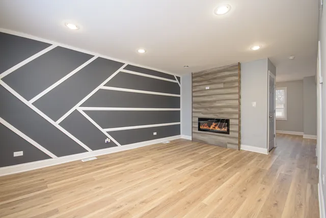 a view of an empty room with wooden floor and a fireplace