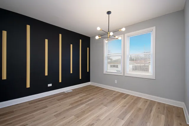 a view of an empty room with window and hardwood floor