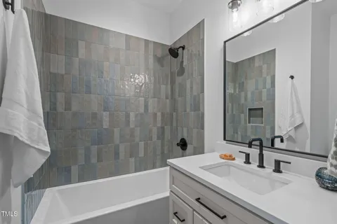 a bathroom with a sink a mirror a bathtub and shower