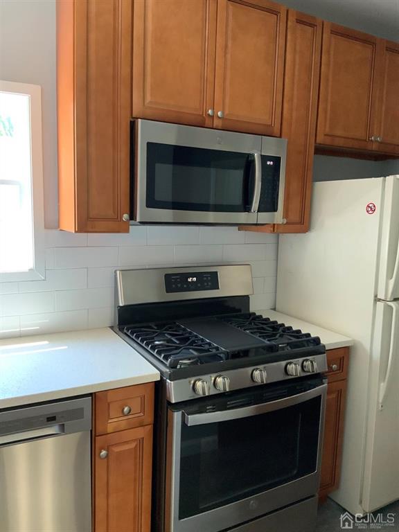 203 Woodbridge Avenue, Unit 2 Metuchen, NJ 08840 - Photo 12 of 13 a kitchen with stainless steel appliances wooden cabinets and a stove top oven