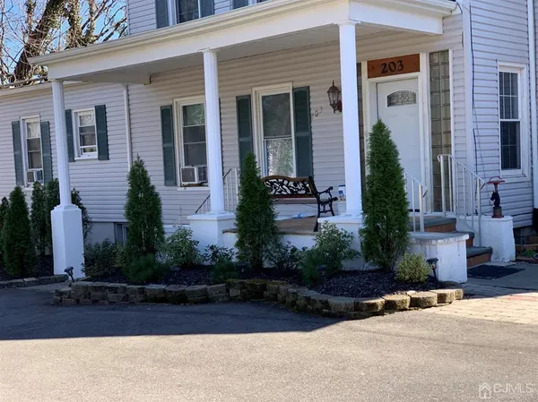 front view of a house with potted plants and a bench
