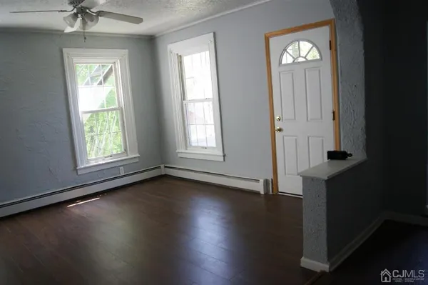 an empty room with wooden floor a chandelier fan and windows