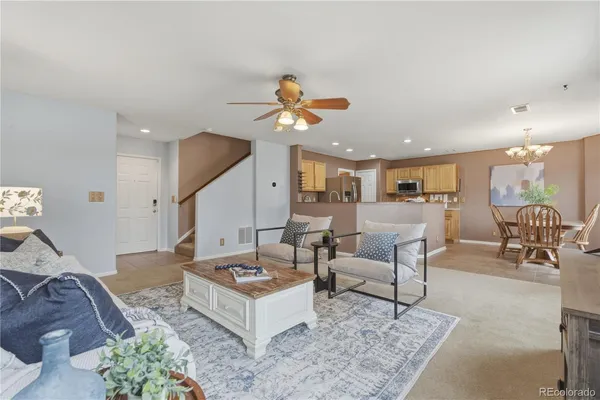 a living room with furniture kitchen view and a chandelier