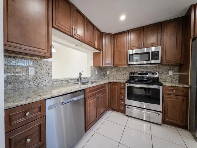 a kitchen with granite countertop wooden cabinets stainless steel appliances and a counter space