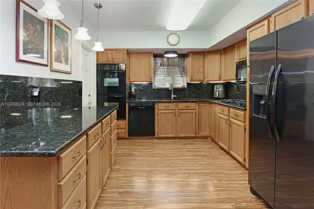 a kitchen with stainless steel appliances granite countertop a refrigerator a stove and a sink