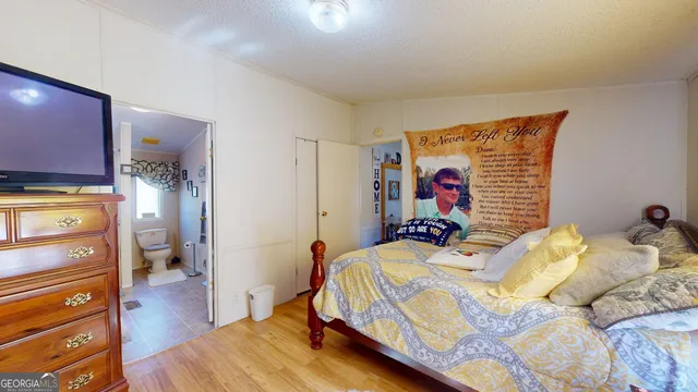 a bedroom with a bed and a flat tv screen on dresser
