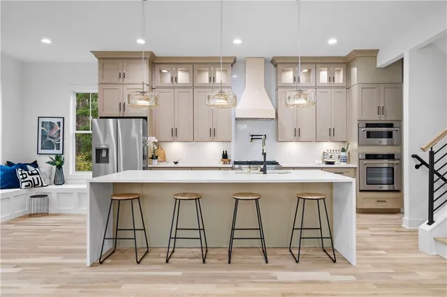 a kitchen with stainless steel appliances granite countertop a dining table chairs stove refrigerator and cabinets