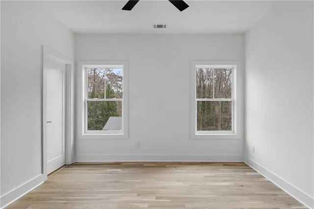 an empty room with wooden floor and windows