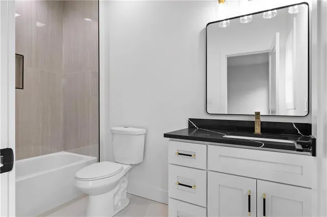 a bathroom with a granite countertop sink a toilet a mirror and vanity