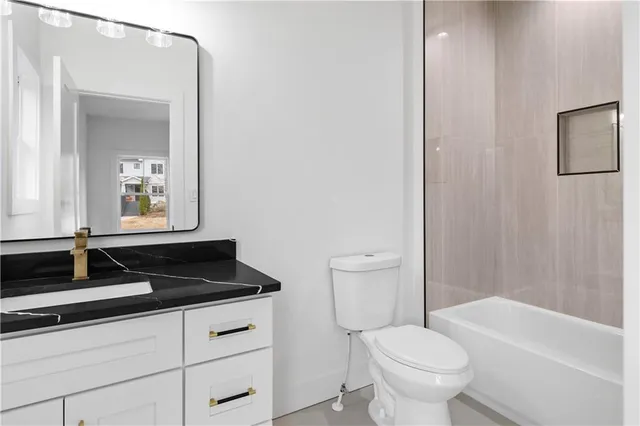 a bathroom with a granite countertop sink toilet a mirror and bathtub