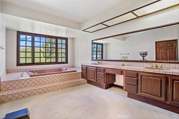a spacious bathroom with a tub double sink and mirror