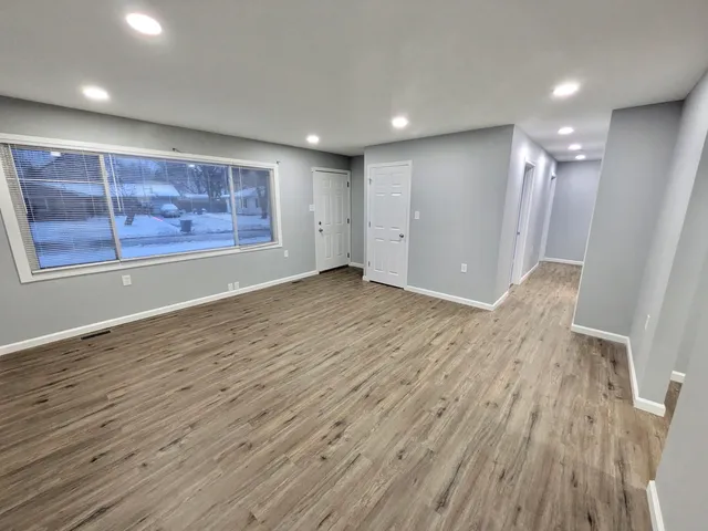 an empty room with wooden floor and natural light