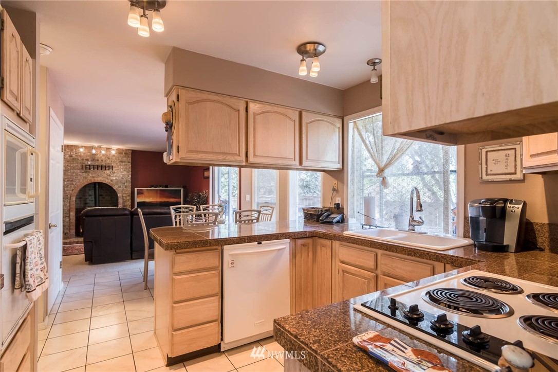 36907 17th Avenue South Federal Way, WA 98003 - Photo 10 of 25 a kitchen with stainless steel appliances a sink a stove a refrigerator cabinets and a dining table with wooden floor