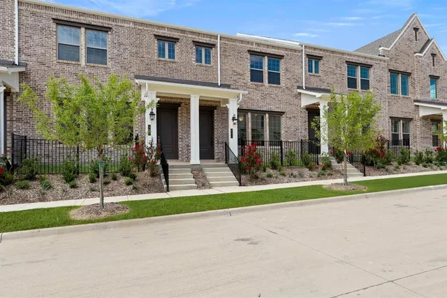 a view of a brick house with a yard plants and palm trees
