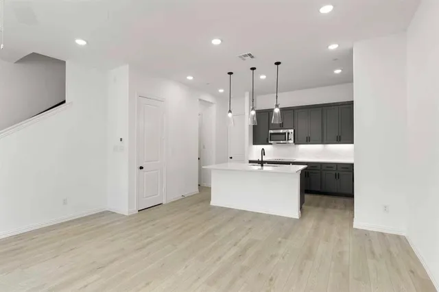 a large white kitchen with a refrigerator a sink dishwasher a stove and a oven with wooden floor