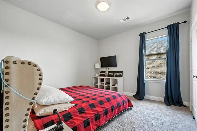 a bedroom with a bed and a flat tv screen on the dresser