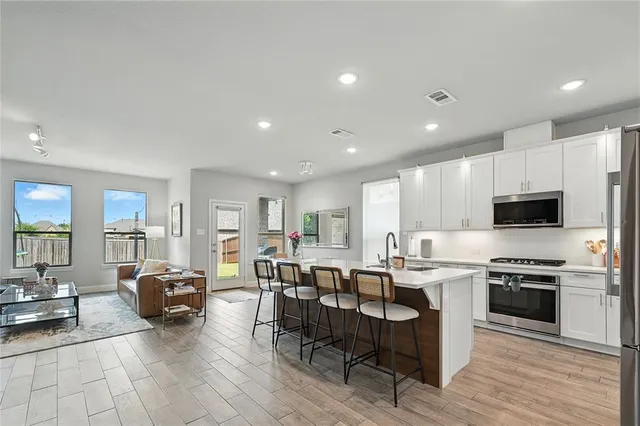 a living room with stainless steel appliances furniture and a kitchen view