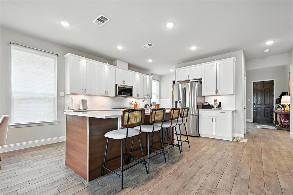1160 Red Hawk Lane Forney, TX 75126 - Photo 6 of 26 a large kitchen with kitchen island white cabinets and stainless steel appliances