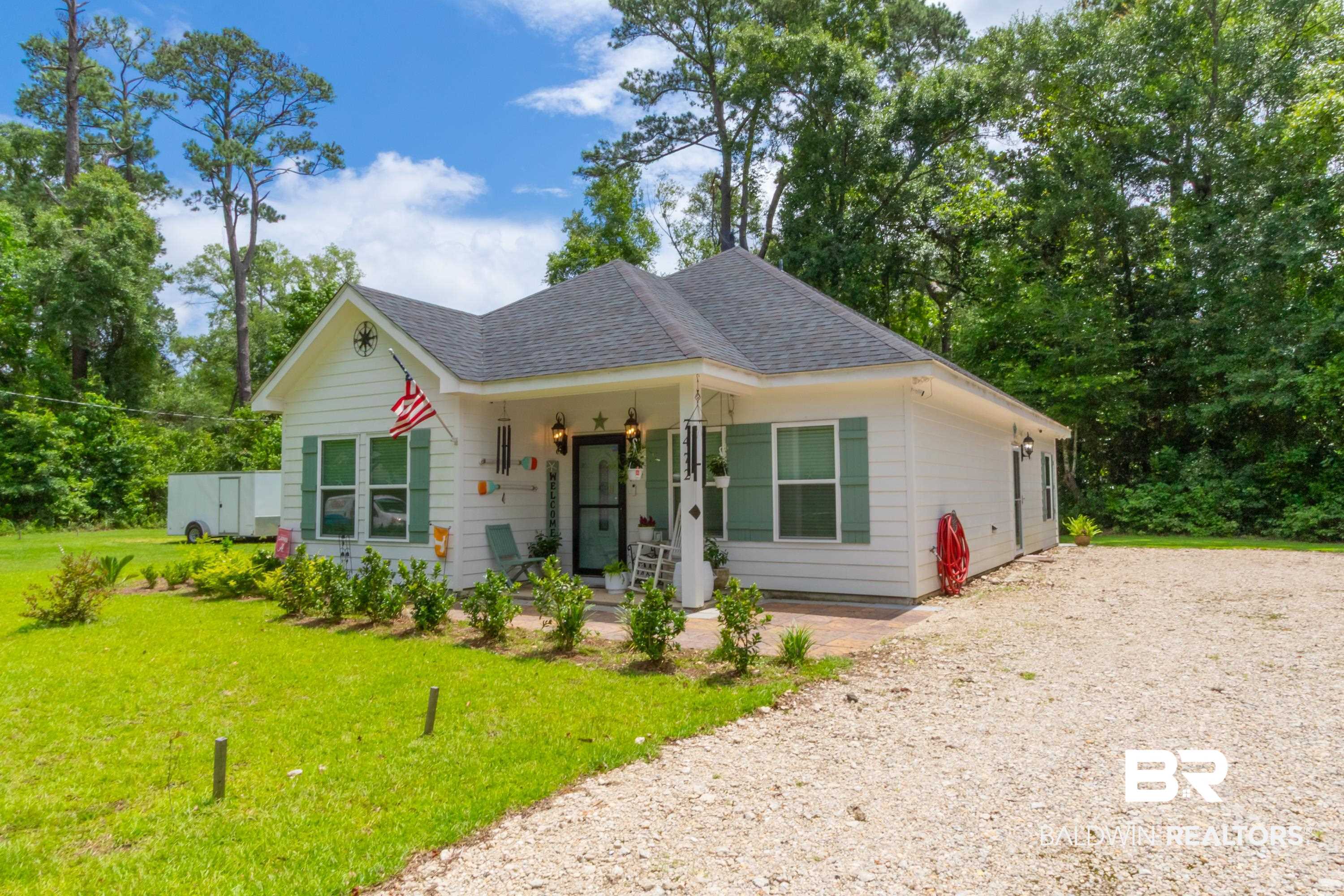 7472 Coopers Landing Road Foley, AL 36535 - Photo 27 of 40 White exterior home featuring a dark gray asphalt shingle roof, green window shutters, a covered porch with white columns, and a gravel driveway