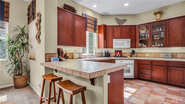 a kitchen with stainless steel appliances granite countertop a table chairs sink and cabinets