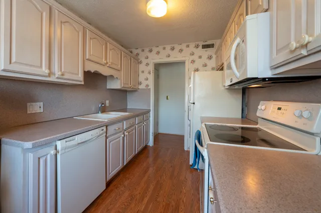a kitchen with granite countertop a sink dishwasher stove and cabinets