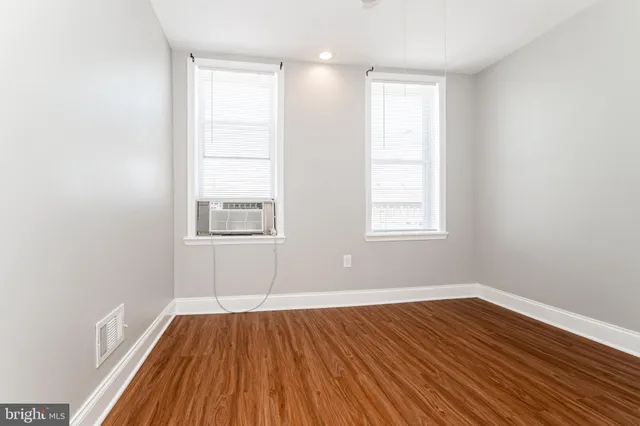 an empty room with wooden floor and windows