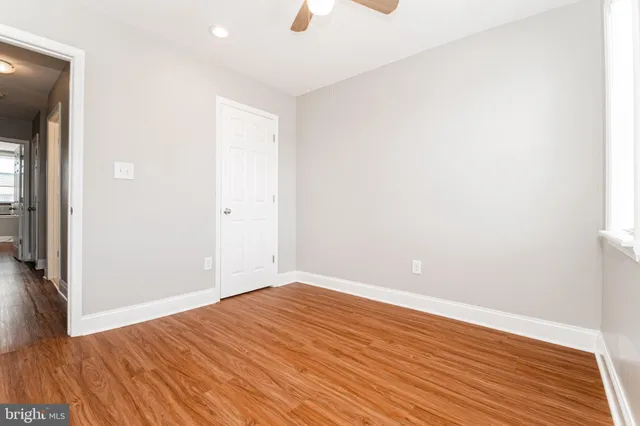 an empty room with wooden floor and a ceiling fan