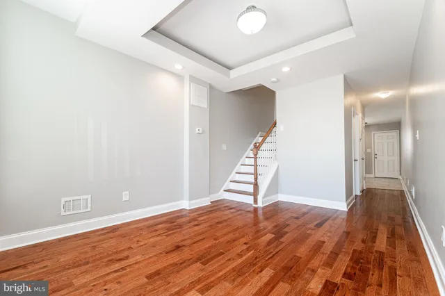 a view of an empty room with wooden floor and stairs