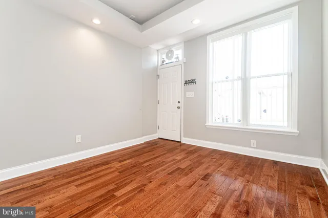 an empty room with wooden floor and windows