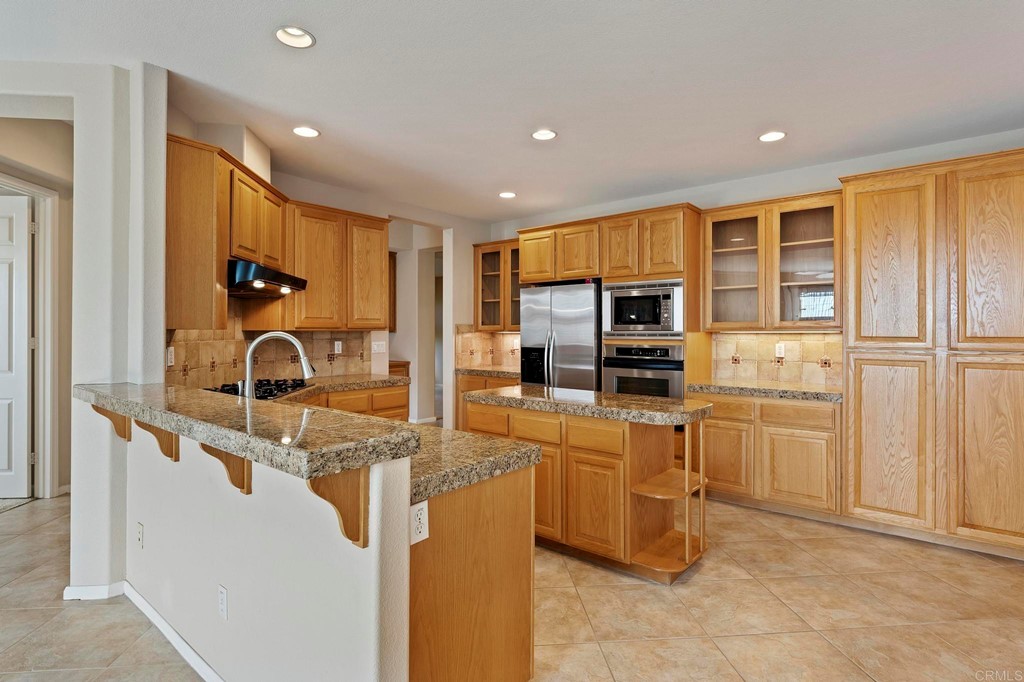1533 Brookside Court San Marcos, CA 92078 - Photo 15 of 46 a kitchen with kitchen island granite countertop a sink and appliances