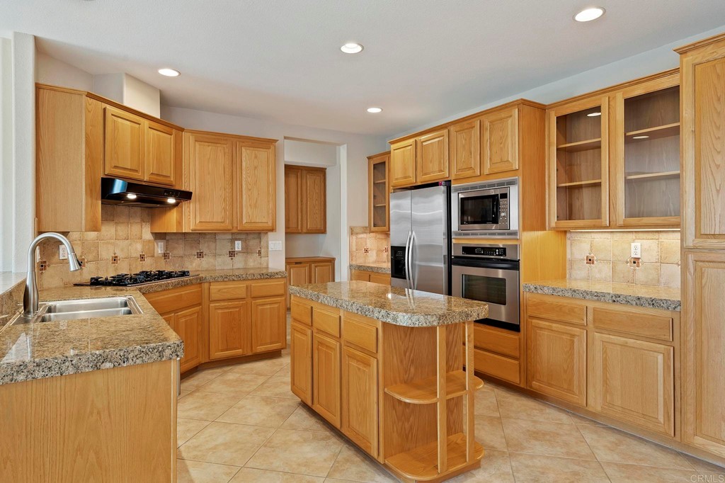 1533 Brookside Court San Marcos, CA 92078 - Photo 19 of 46 a kitchen with stainless steel appliances granite countertop a stove top oven a sink dishwasher and a refrigerator with wooden cabinets