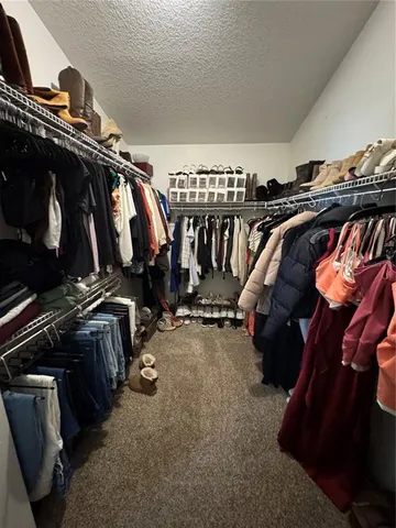 a view of walk in closet with clothes and shoes