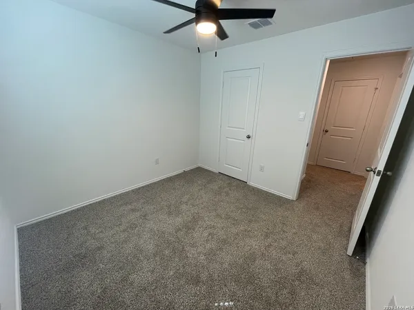 an empty room with a ceiling fan and window
