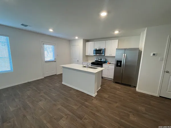 a kitchen with a refrigerator a stove top oven a counter space and a window