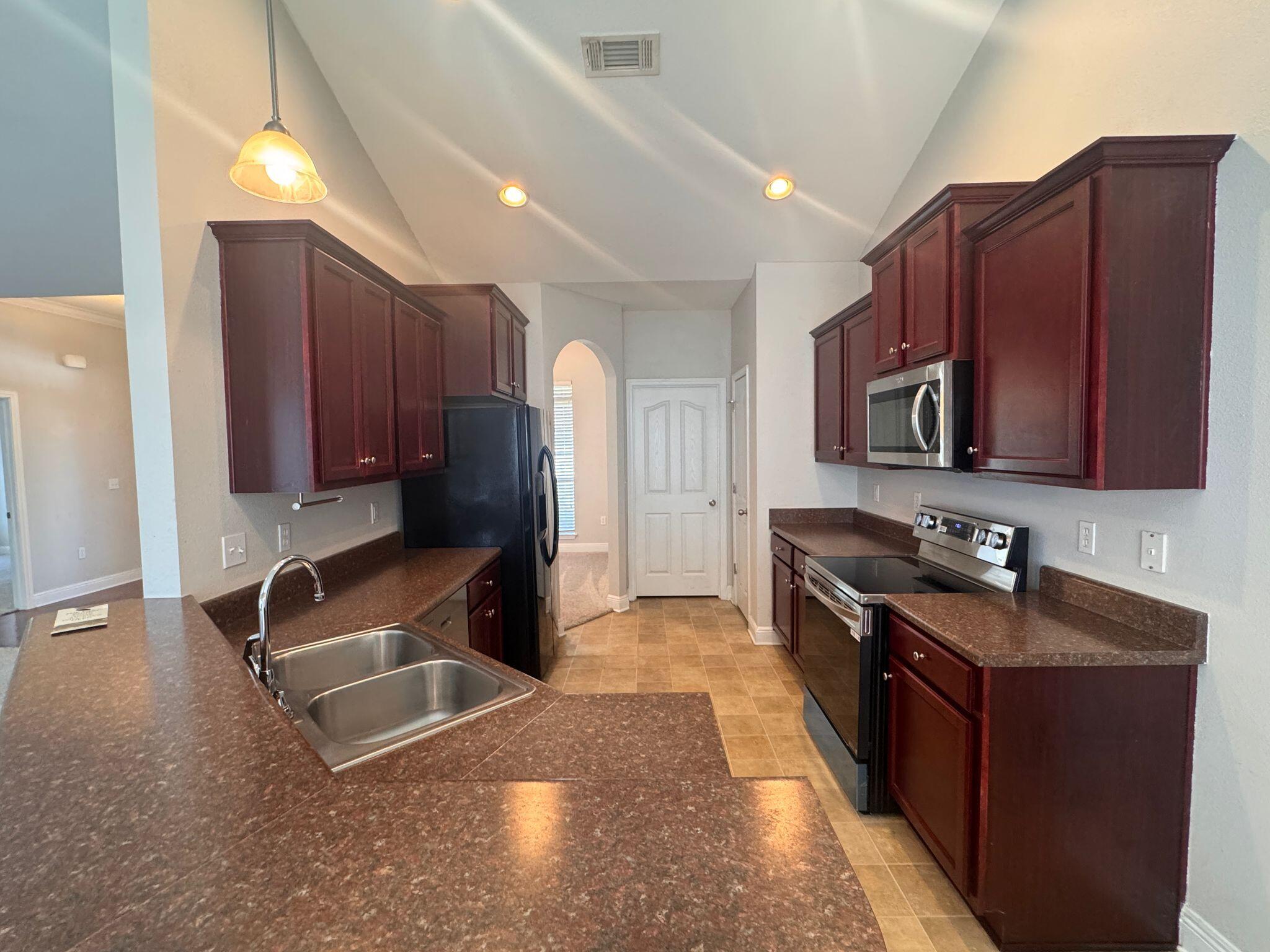 744 Lime Lane Crestview, FL 32536 - Photo 9 of 25 a kitchen with granite countertop wooden cabinets a refrigerator and a sink