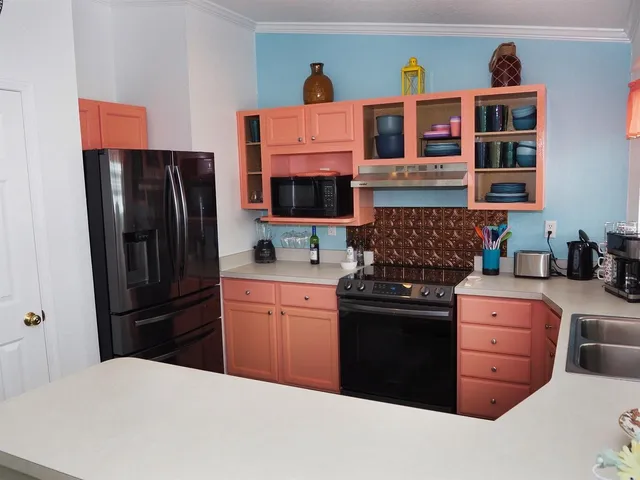 a living room with stainless steel appliances furniture a rug and a large window