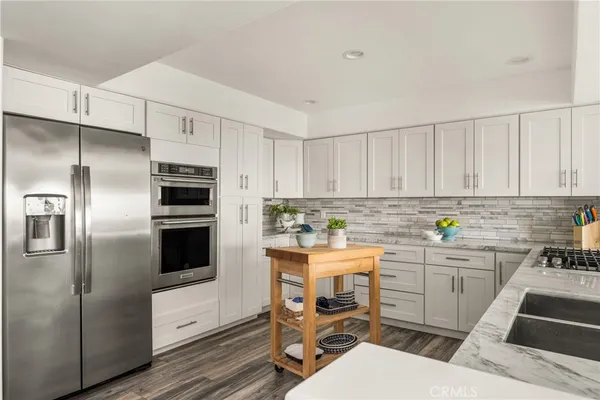 a kitchen with stainless steel appliances a table chairs and a refrigerator