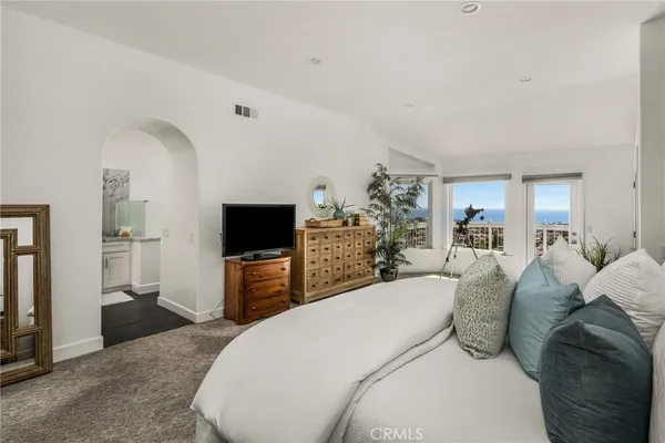 a spacious bedroom with a bed and a flat screen tv