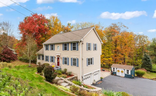 a view of a white house with a yard and table and chairs under an umbrella