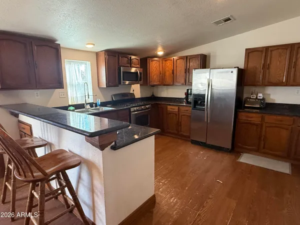 a kitchen with stainless steel appliances granite countertop a stove a refrigerator a sink a stove with island and chairs