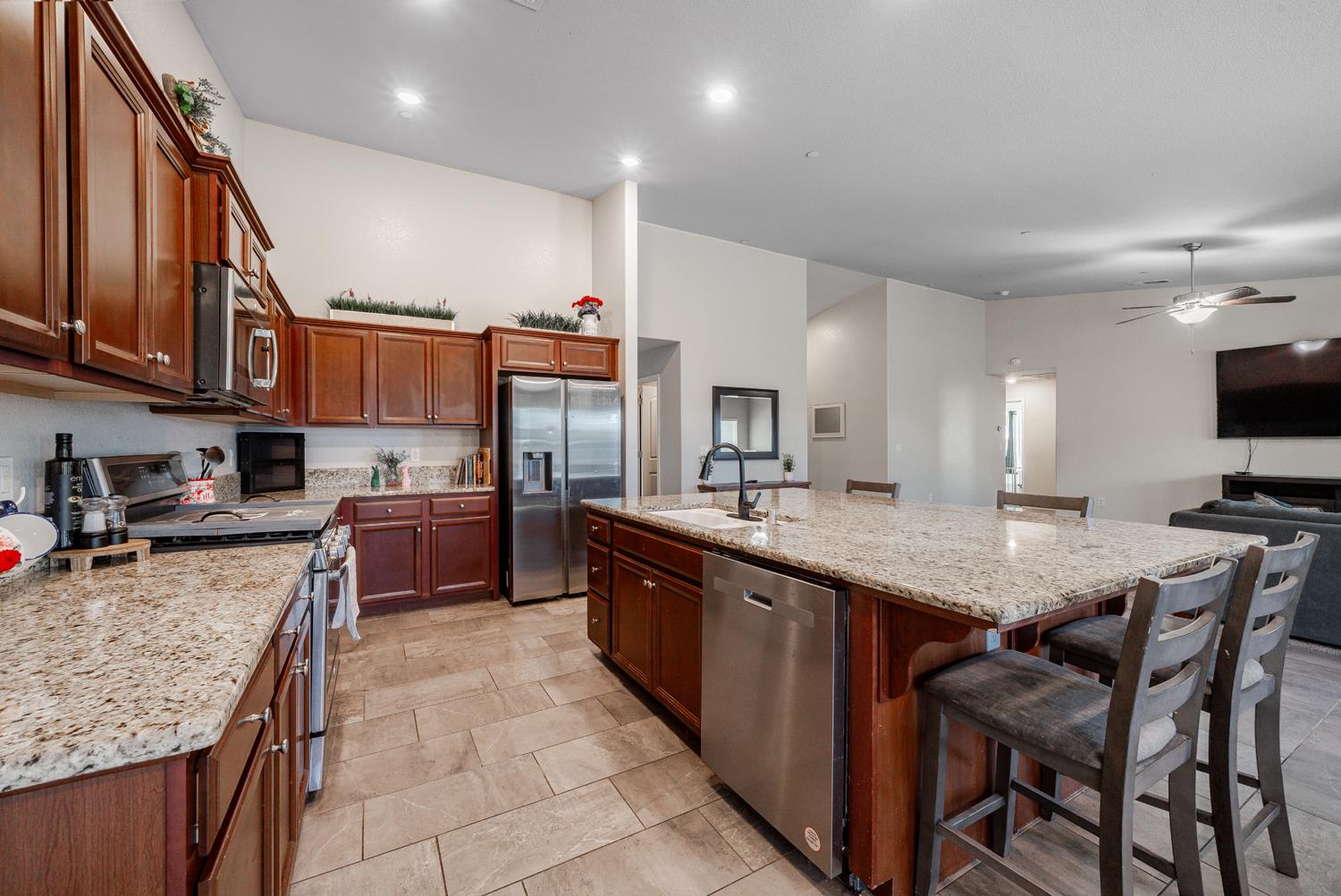 3133 4th Street Sanger, CA 93657 - Photo 12 of 33 a kitchen with stainless steel appliances granite countertop a table chairs sink refrigerator and cabinets