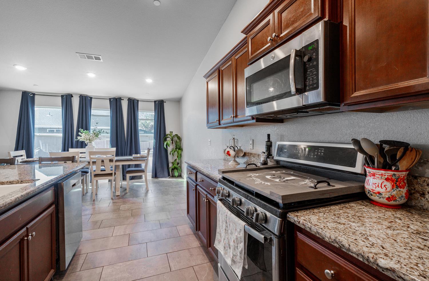 3133 4th Street Sanger, CA 93657 - Photo 14 of 33 a kitchen with stainless steel appliances granite countertop a stove top oven a sink a dining table and chairs